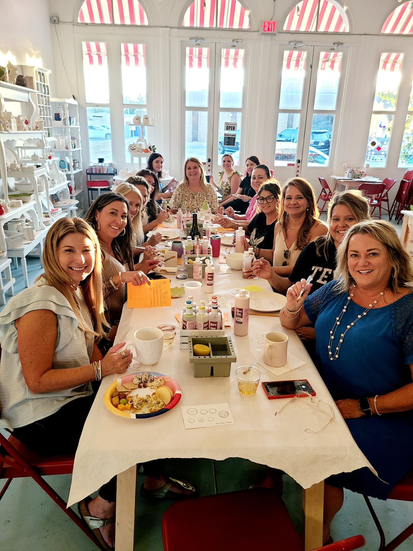 A birthday group painting pottery around a long table at The Cherry on Top